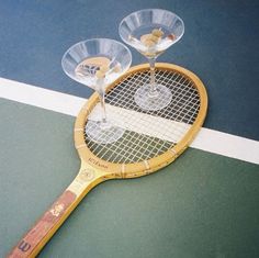 two wine glasses sitting on top of a tennis racket