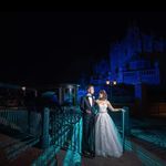 a bride and groom standing on a bridge at night