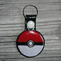 a pokemon ball keychain is shown on a wooden table with a white and black background