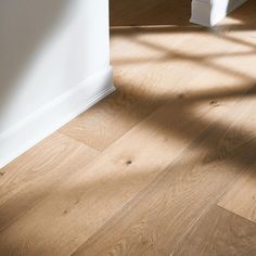 an empty room with wooden floors and white walls, sunlight coming through the window onto the floor