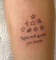 a woman's leg with stars and the words lights will guide you home on it