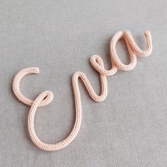 the word snake spelled out in crochet on a gray surface with a white background