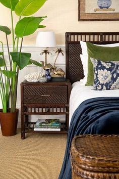 a bedroom with a bed, nightstand and plant in the corner on the side table