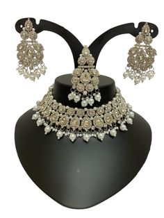 This Silver Jewelry Set exudes elegance and sophistication, making it a perfect choice for weddings, festive events, or grand celebrations. The intricate craftsmanship showcases delicate silver details adorned with Kundan and pearl accents, creating a regal and timeless appeal. Whether paired with traditional or fusion outfits, this stunning necklace and matching earrings add a touch of luxury to your ensemble. Available now with quick international shipping! About this Silver Asian Jewelry Set Silver Kundan Necklace For Reception With Elegant Design, Silver Bridal Sets For Formal Festive Occasions, Festive Silver Bridal Sets For Formal Occasions, Festive Silver Bridal Sets, Traditional Silver Bridal Accessories For Marriage, Heavy Silver Bridal Sets For Formal Occasions, Silver Bridal Sets With Intricate Design For Reception, Silver Kundan Jewelry Sets For Reception, Formal Silver Kundan Sets