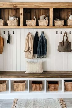 a bench with baskets and coats hanging on the wall next to it is filled with coat hooks