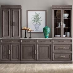 an empty room with wooden flooring and gray cabinetry on the wall, along with a green vase