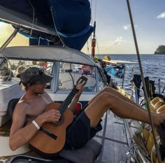 a man sitting on top of a boat holding a guitar