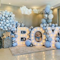 a teddy bear is sitting in the center of balloons that spell out the word boy