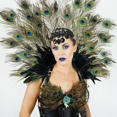 a woman with peacock feathers on her head and blue eyeshade, wearing a black corset