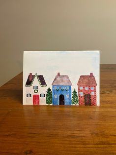 a card with houses painted on it sitting on a table