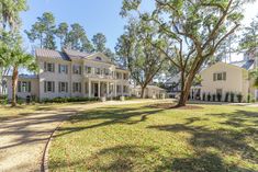 a large white house surrounded by trees and grass