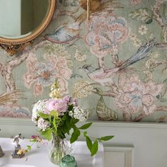 a vase filled with flowers sitting on top of a bathroom counter next to a mirror