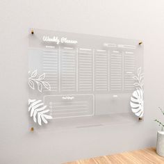 a clear glass magnetic calendar on a wall next to a vase with a plant in it