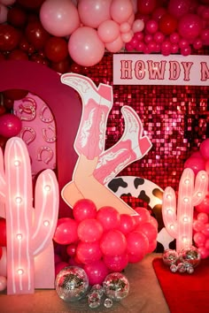 pink balloons and decorations are on display in front of a backdrop that reads, howdy'm