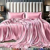 a bed with pink sheets and pillows on top of it next to a night stand