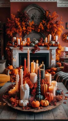 a table topped with candles and pumpkins on top of a wooden table next to a fireplace