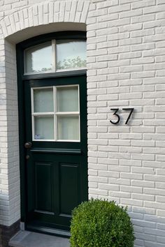 a green door is in front of a white brick building with the number 377 on it