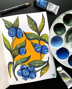 a painting with blueberries and green leaves on it next to some watercolor paints