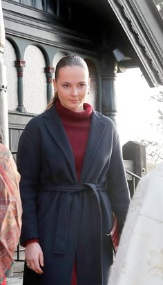 a woman in a black coat is standing outside