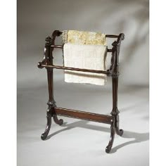 an antique wooden towel rack with two towels hanging on it's sides and a white blanket draped over the top