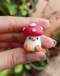 a hand holding a tiny mushroom toy in it's palm