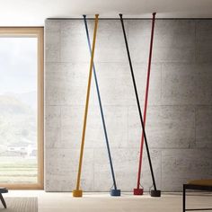 three different colored brooms in front of a window