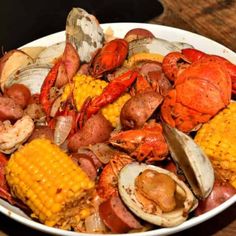 a white bowl filled with seafood and corn on the cob