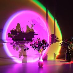 a vase with flowers in it sitting on a table next to a flower pot and a tripod light