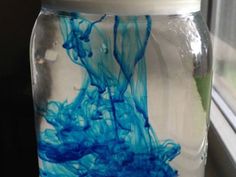 a glass jar filled with blue liquid sitting on top of a window sill