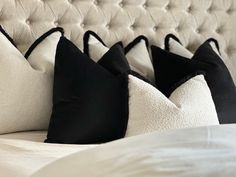 four black and white pillows are lined up on a bed with an off - white headboard