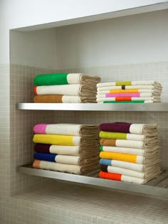 towels are stacked on shelves in a bathroom