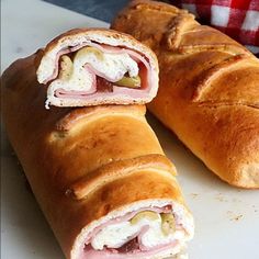 two sandwiches cut in half on a cutting board next to a red and white checkered napkin