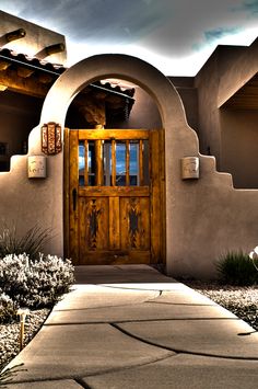 an adobe - style house with wooden doors and arched doorways is pictured in this image