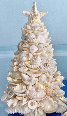 a christmas tree made out of seashells and starfish on a blue table