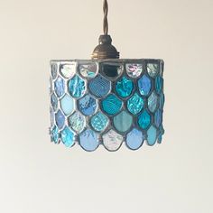 a blue and white lamp hanging from a light fixture with a chain attached to it