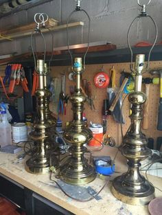 three brass lamps sitting on top of a wooden table next to other items and tools