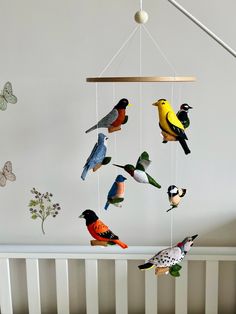 several birds are hanging from a mobile in a crib