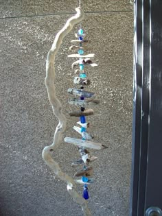 a wind chime hanging from the side of a building with rocks and glass beads