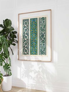 a green and white wall hanging over a wooden table next to a potted plant