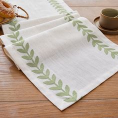 two napkins sitting on top of a wooden table next to a cup and saucer