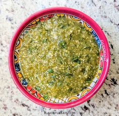 a red bowl filled with green food on top of a counter