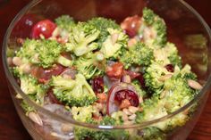 a glass bowl filled with broccoli, grapes and other vegetables on top of a wooden table