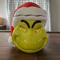 a ceramic grin face with a santa hat on it's head sitting on a wooden table