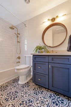 a white toilet sitting next to a bath tub in a bathroom under a round mirror