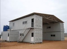 a building made out of shipping containers with stairs leading up to the top floor and windows