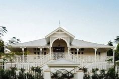 a large white house sitting next to a lush green forest filled with trees and bushes