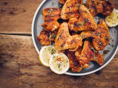 chicken wings on a plate with lemon wedges