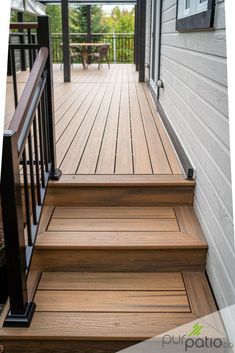 a wooden deck with black handrails and steps leading up to the front door