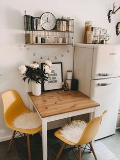 a kitchen table with two chairs next to it and a white refrigerator in the background