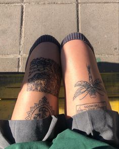 someone with tattoos on their legs sitting on a bench